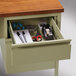 A drawer in a Hirsh Industries left corner pedestal desk kit with office supplies including a pen, scissors, and tape.