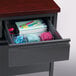 A black pedestal desk with a drawer full of stationery including a file cabinet and pen holder.