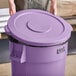 A person holding a purple Lavex trash can lid.