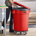 A man using a dolly to open a Lavex red trash can in a school kitchen.