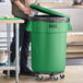 A man standing next to a green Lavex commercial trash can.