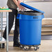 A man opening a blue Lavex 32 gallon commercial trash can in a school kitchen.