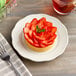 An Acopa ivory scalloped stoneware plate with a strawberry tart on it.