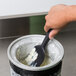 A hand using a Zeroll ice cream spade to scoop white ice cream.