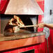 a person holding a brush in a brick oven