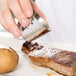 A hand holding an American Metalcraft Hammered Stainless Steel Round Sauce Cup over a steak.