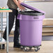 A man standing next to a purple Lavex commercial trash can.