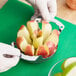 A person using a Choice apple corer/slicer to cut up apples in a glass bowl.