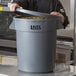 A man in a chef's uniform standing in front of a large gray Lavex trash can.