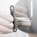 A person in white gloves holding a Nemco separating blade for a curly fry cutter.