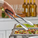 A person using American Metalcraft wavy stainless steel tongs to serve food.