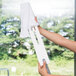 A person using a Unger ProFlex duster with a white microfiber sleeve to clean a window.