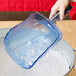 A person using a Rubbermaid blue ice scoop to pour ice into a bucket.