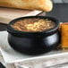 A bowl of French onion soup and bread on a plate.