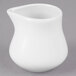 A Tuxton porcelain white creamer pitcher with a small handle on a gray surface.