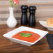 A CAC Super White square porcelain bowl filled with red sauce with a leaf on top.