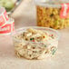 A translucent plastic deli container with pasta and cheese on a counter.