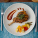 A Tuxton TuxTrendz matte white china plate with a plate of food with a fork and knife.