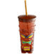 A translucent brown plastic tiki cup with a straw and a tiki face on it.