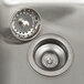 A close up of the drain of an Advance Tabco stainless steel drop-in sink with three compartments.