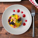 A Tuxton TuxTrendz matte gray coupe china bread and butter plate with a fruit tart and a fork on a table.