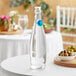 A clear Libbey glass bottle with a blue wire bail lid on a table.