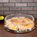 A Sabert clear plastic high dome lid on a tray of sandwiches and chips.