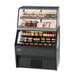 A black Federal Industries refrigerated display case with food on it.