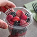A clear plastic flat non-vented lid on a cup filled with mixed berries.