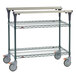 A Metro green metal cart with two shelves and wheels.