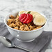 A Schonwald round porcelain bowl filled with cereal and fruit with a spoon next to it.
