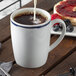 A Schonwald dark blue porcelain mug filled with coffee and milk on a white background.