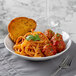 A Schonwald Structure Grey porcelain deep coupe plate with a plate of pasta and meatballs on a table.