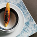 A Schonwald blue square porcelain coupe plate with a slice of papaya on top.