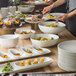 A table with a bowl of food and Schonwald bone white porcelain tasting spoons.