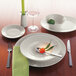 A Schonwald white porcelain plate with a fork on a wood table.