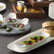 A table with a stack of rectangular white porcelain dishes.
