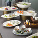 A Schonwald bone white porcelain bowl filled with food on a table.