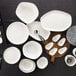 A group of Schonwald white oval coupe platters on a wood surface.