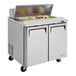 A Turbo Air stainless steel sandwich prep table with food inside.