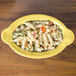 A Fiesta Sunflower oval china baker filled with pasta and vegetables on a table.