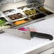 A knife on a cutting board with food in containers.