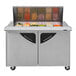 A Turbo Air stainless steel refrigerated sandwich prep table with glass doors filled with food containers.