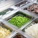 A Turbo Air refrigerated sandwich prep table with containers of vegetables on a counter.