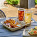 An EcoChoice molded fiber take-out carrier with two drinks and a large tray of food on a table.