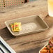 A rectangular molded fiber tray with a textured bottom, shown holding two mustard packets on a wooden table.