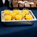 A Vollrath egg poacher tray holding glasses of orange juice on a table.