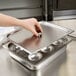 A hand holding a stainless steel tray with four cups.