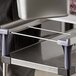 A person using a Metro PrepMate MultiStation Magic Ring on a grey counter to hold metal containers.