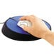 A hand using a computer mouse on a cobalt blue circular mouse pad with black trim.